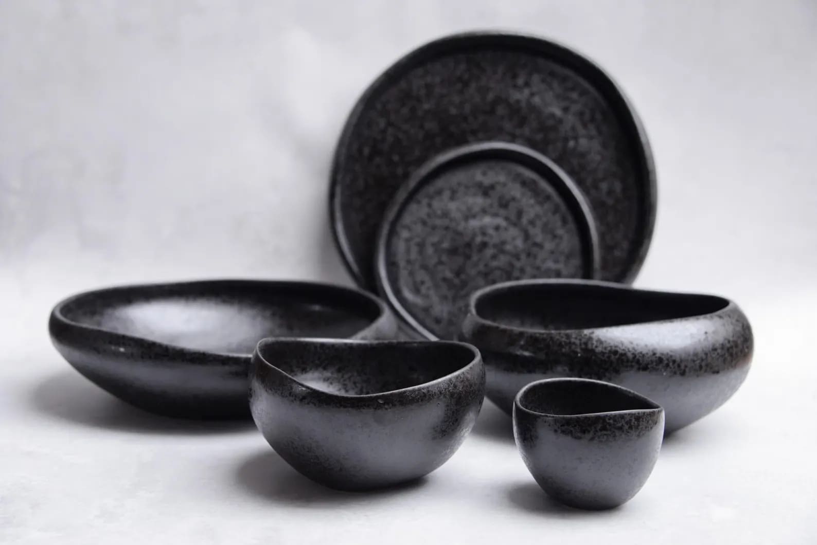 Set of black ceramic cups and plates on wooden table