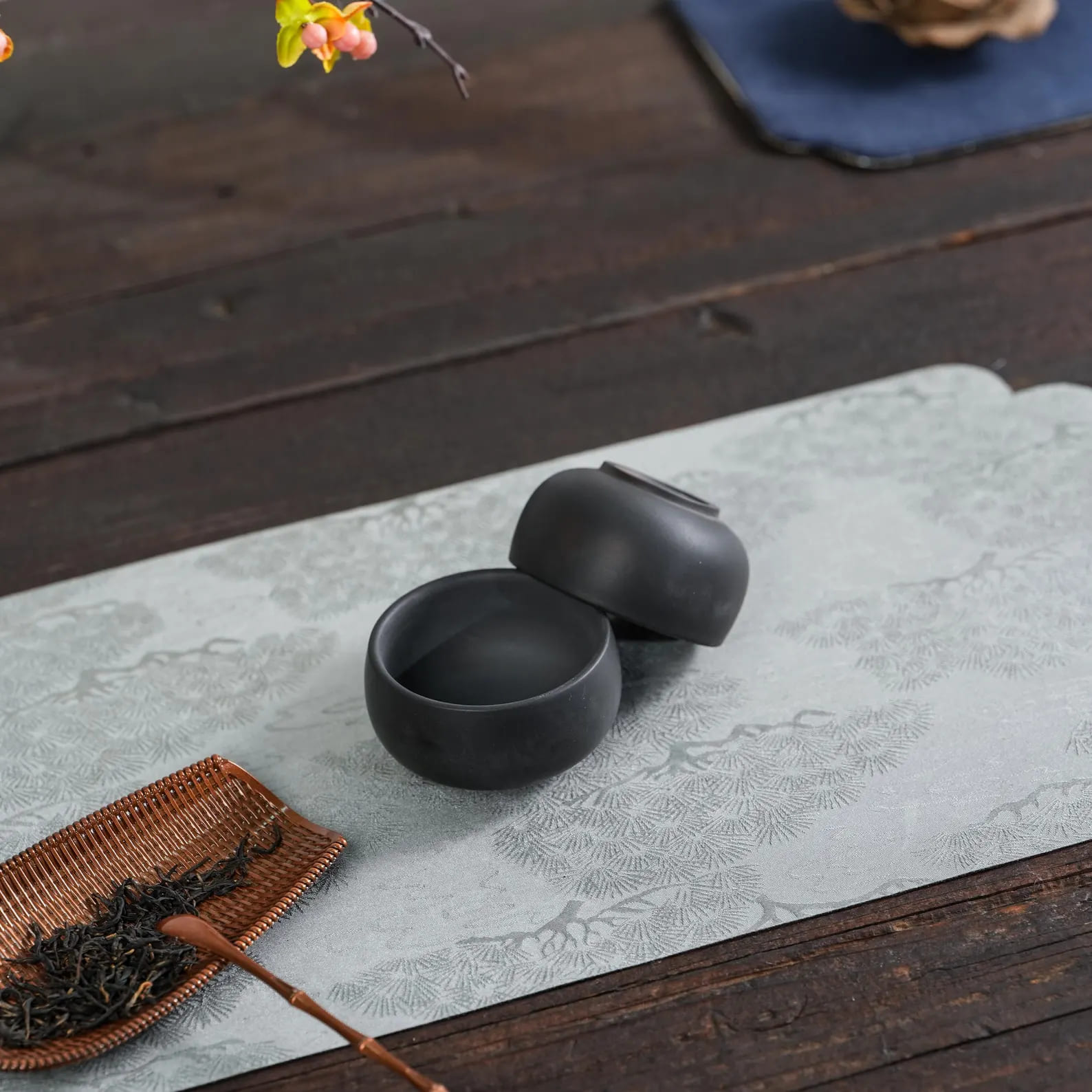 Two matte black ceramic plates with herbs on dark surface